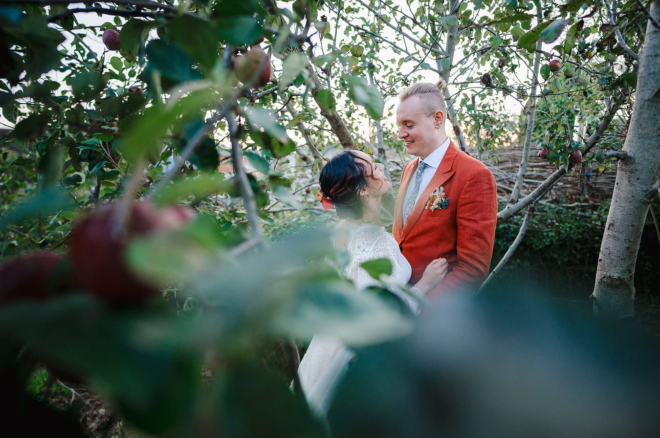 The bride and groom get amongst the apple trees for their couple photos by Bristol Wedding Photographer, Jake Timms Photography