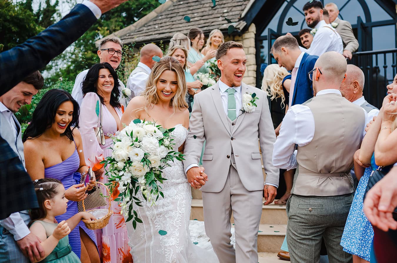 The bride and groom walk through the wedding confetti aisle by London Wedding Photographer, Jake Timms Photography