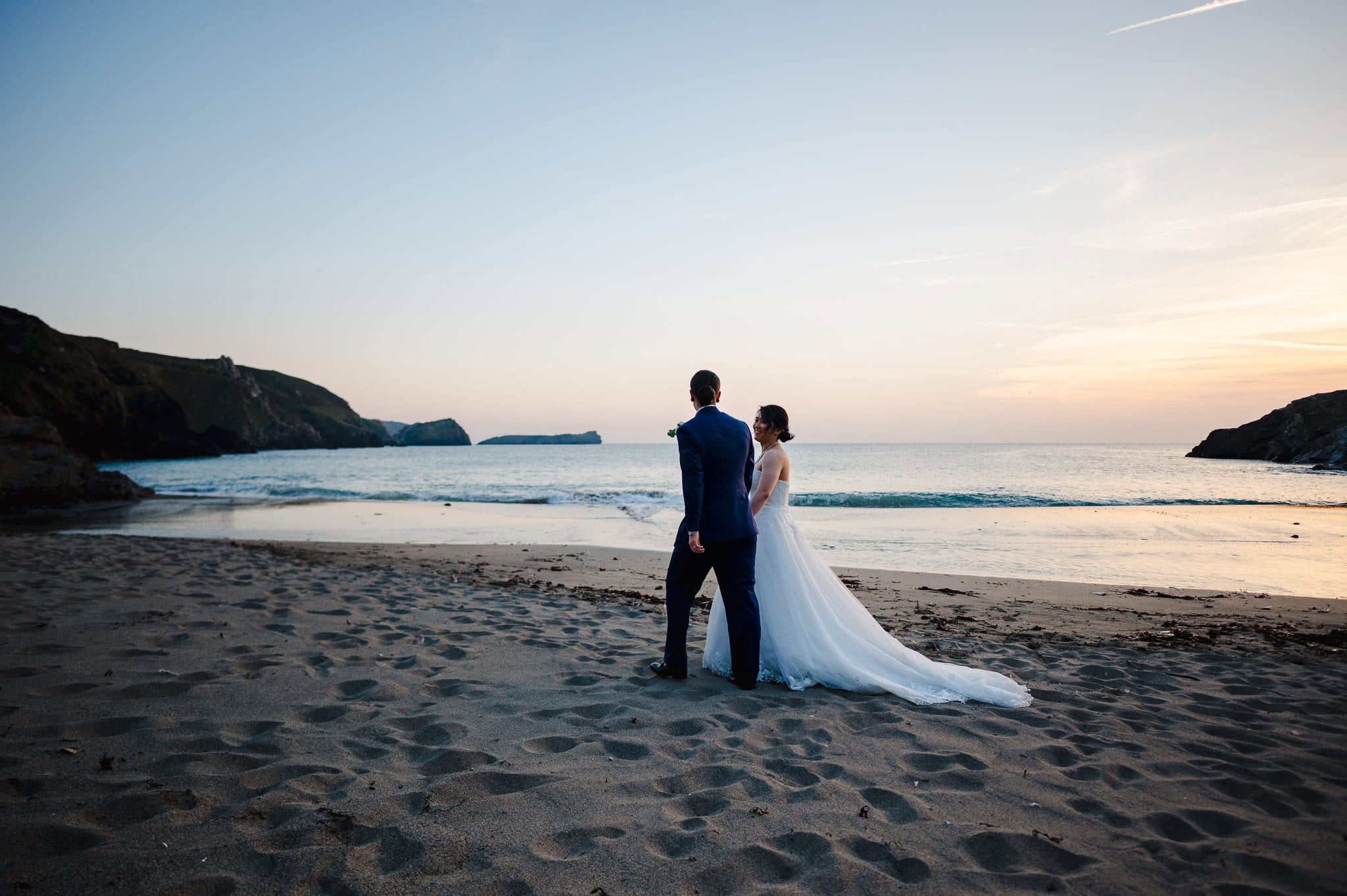 The happy couple enjoy celebrating their wedding day with a walk on the beach below Polurrian On The Lizard - Wedding Video