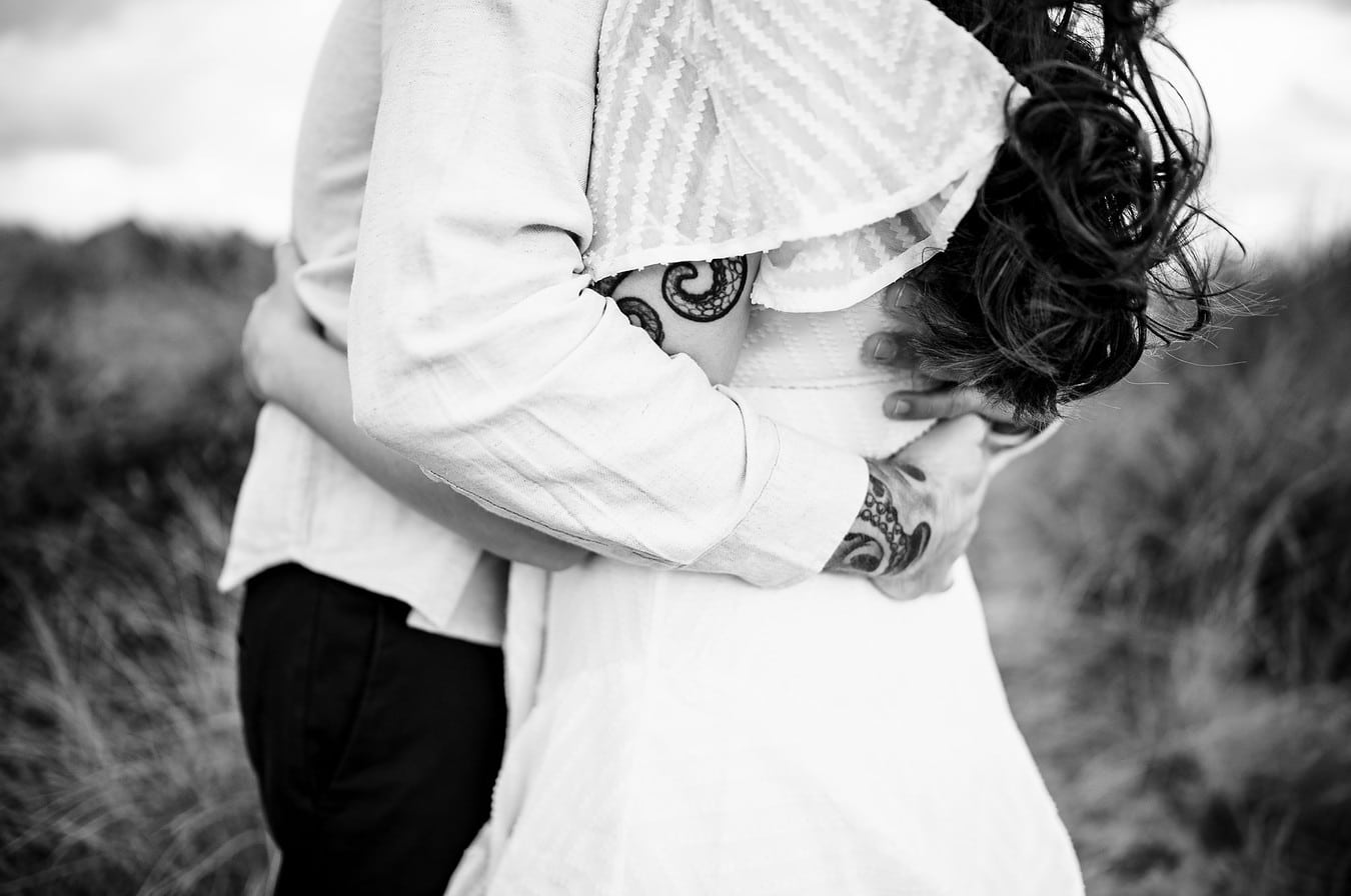 Arms wrapped around each other on a beach in Cornwall
