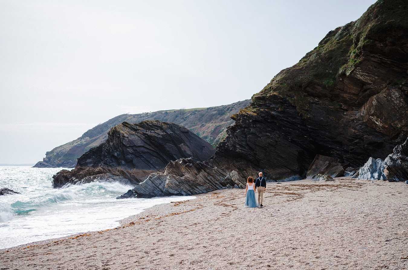 Walking down the sandy beach during their elopement celebrations in Cornwall