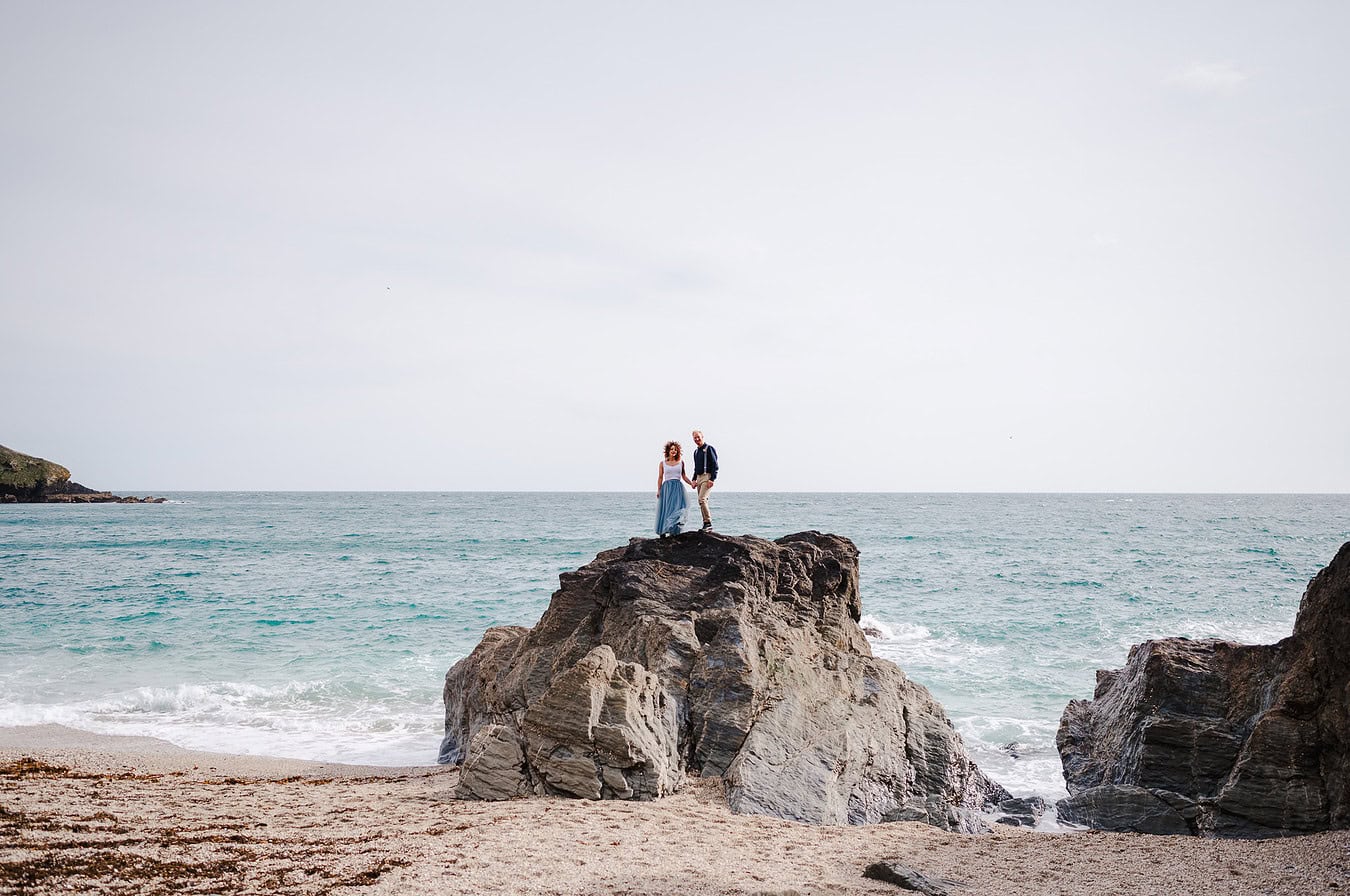 Climbing onto the rocky coast of Cornwall to stand tall above the waves - Elopement Portfolio
