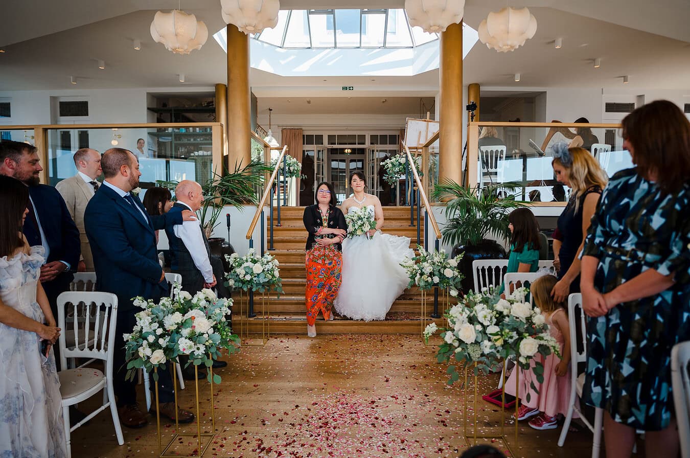 Walking down the stairs towards the aisle at Polurrian - Wedding Portfolio