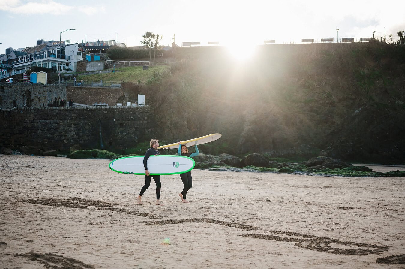 Carrying surfboards during their engagement photo shoot
