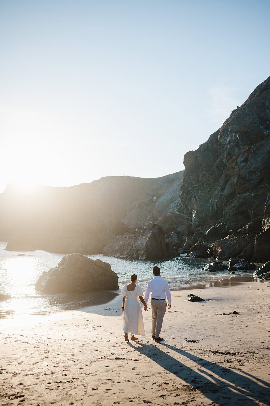 Walking along the golden sandy beach in Cornwall during their proposal celebrations