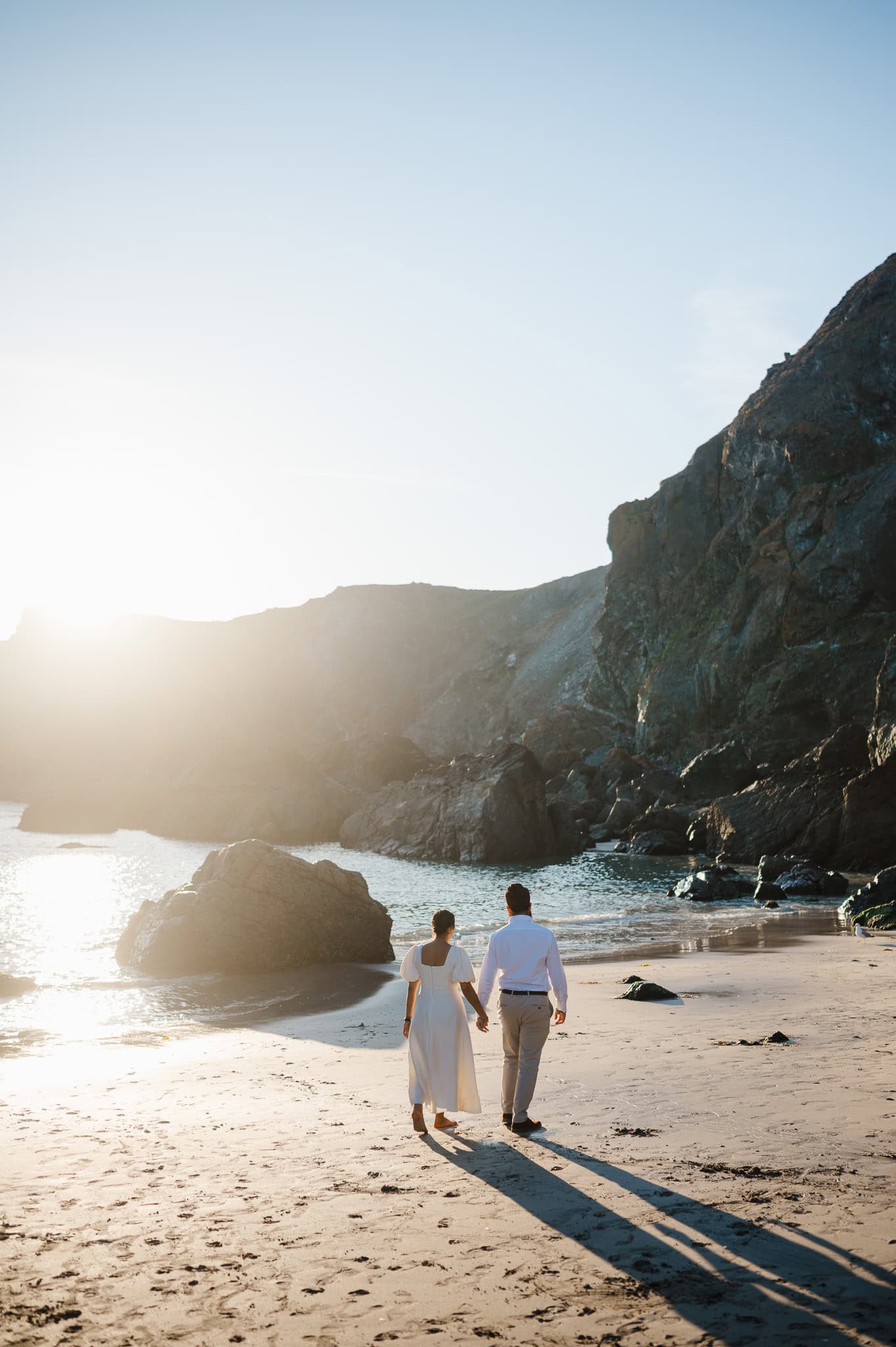 Walking along the golden sandy beach in Cornwall during their proposal celebrations