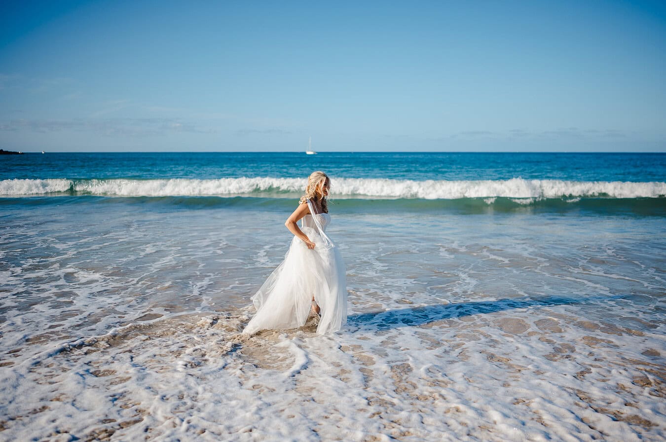 Bride walking through the water in Cornwall in her wedding dress