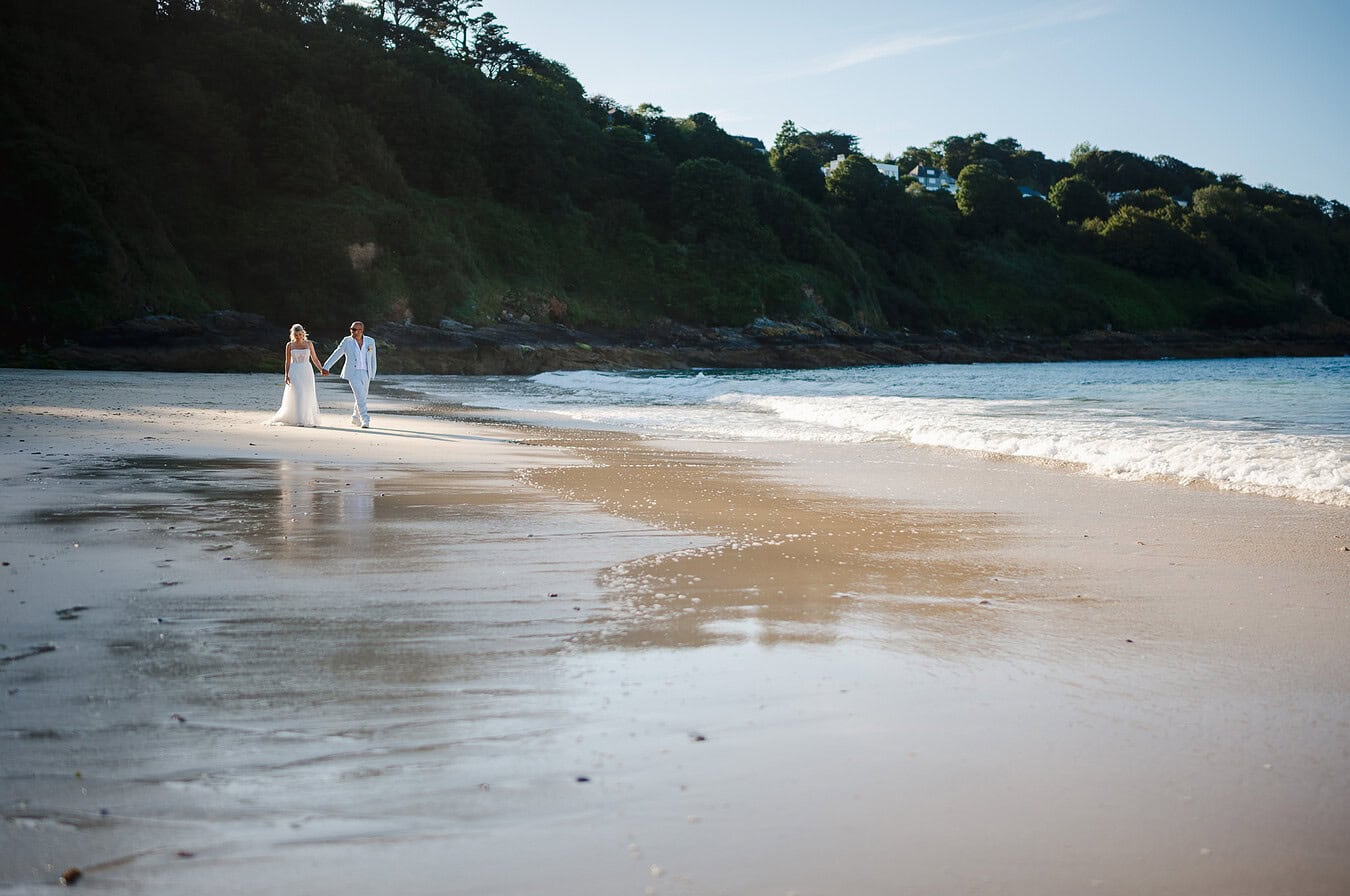 Beach wedding couple walks during their sunset
