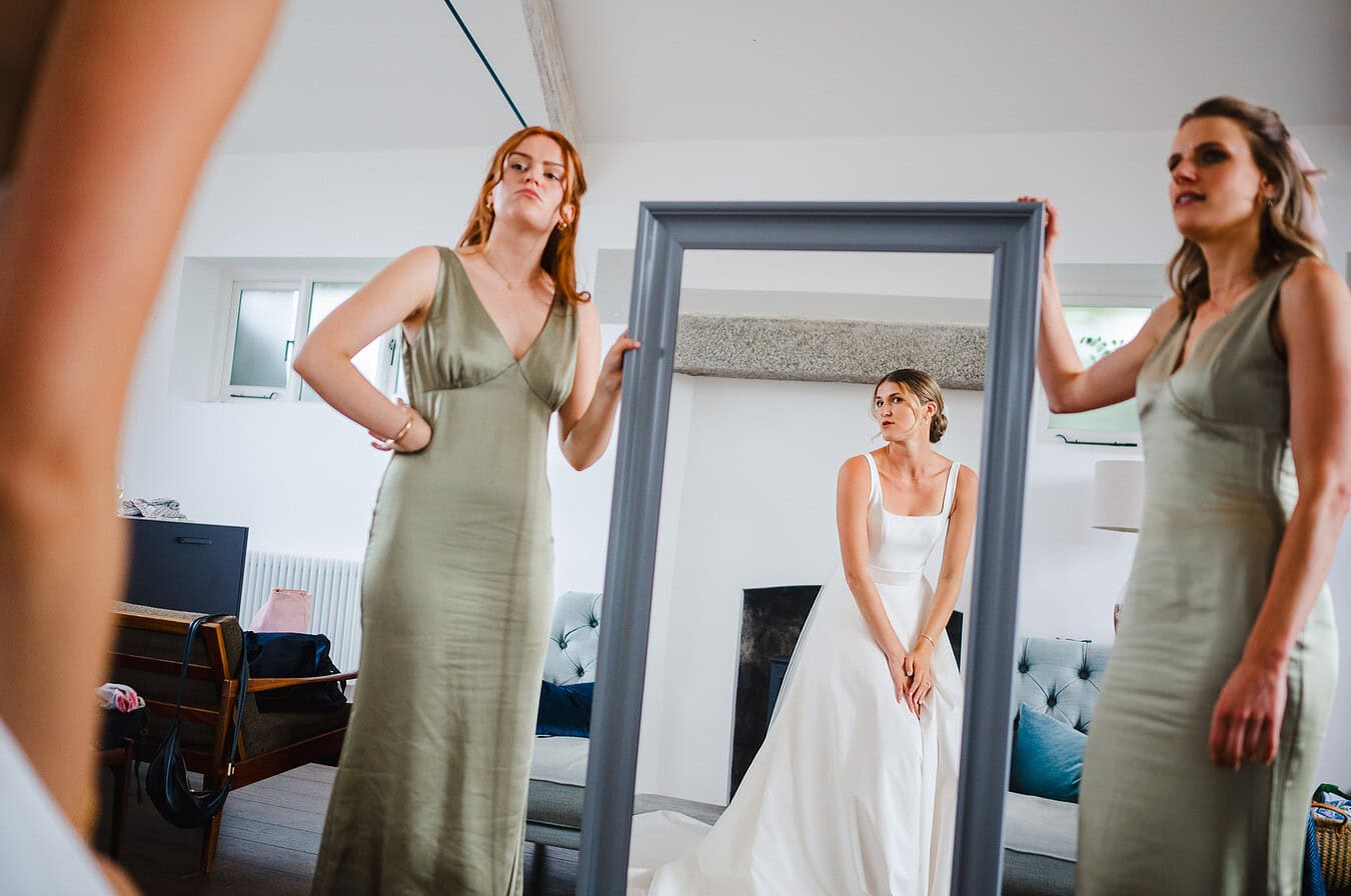 Bride looks into the mirror that the bridesmaids hold up