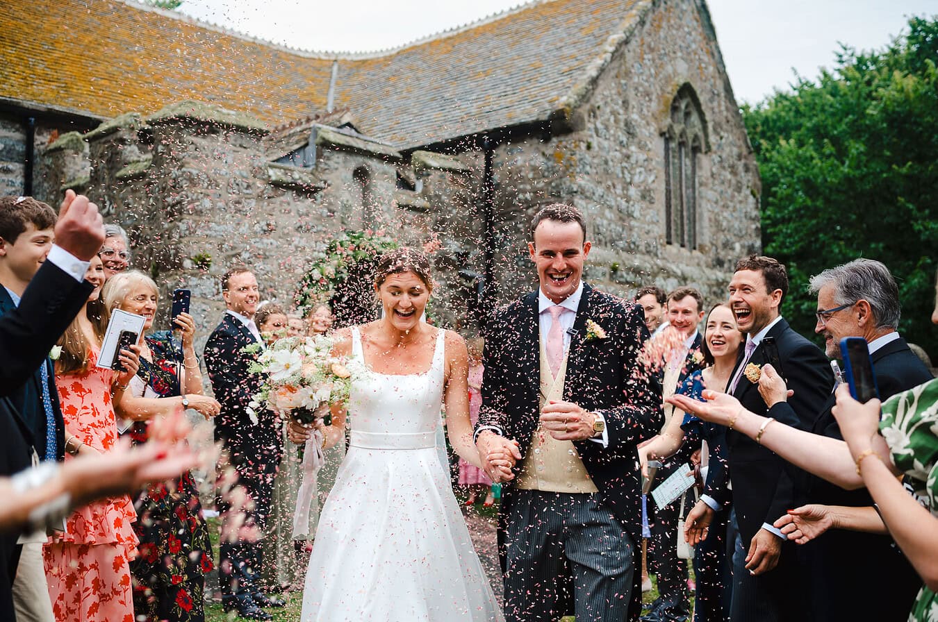 The wedding confetti pours over the couple outside the wedding church