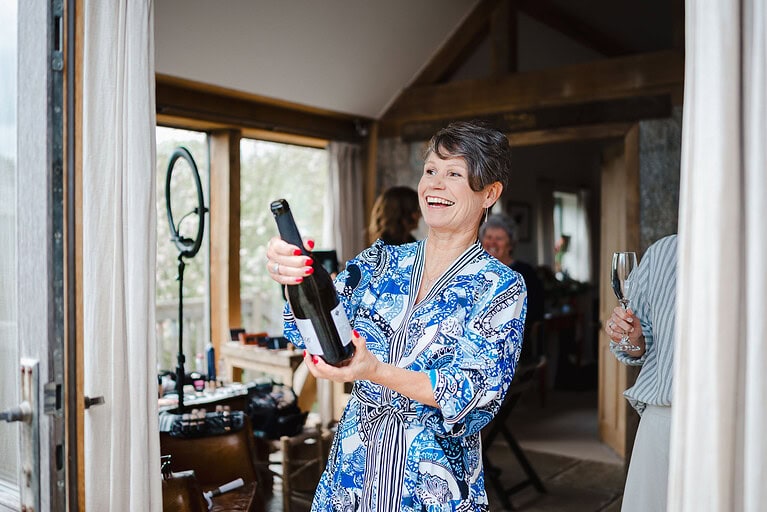Mother of the bride popping the wedding champagne bottle