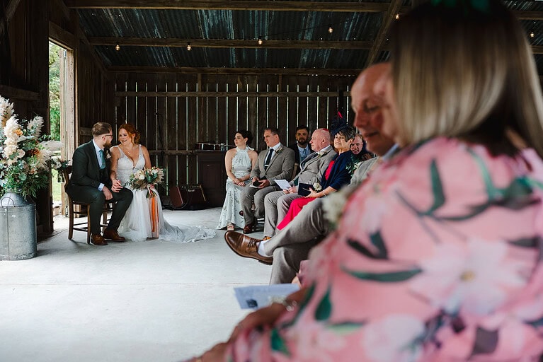 Bride and groom take a seat surrounded by loved ones at Nancarrow Farm