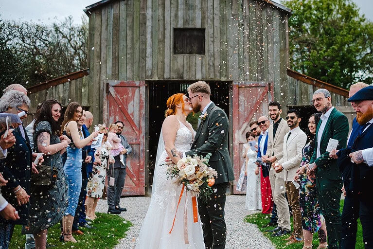 Stopping for a kiss as the happy couple walk down the wedding conffetti aisle