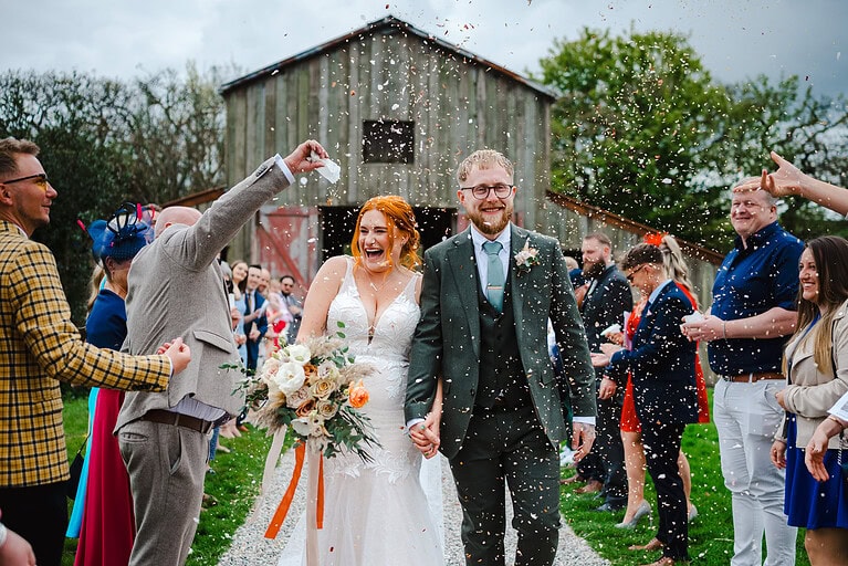 Getting covered in wedding confetti outside Nancarrow Wedding Farm Barn