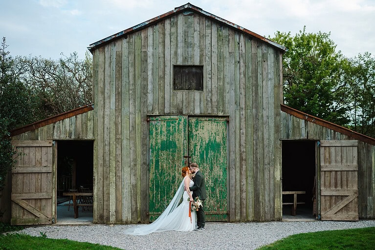 The newlyweds share a kiss outside the Nancarrow Wedding Barn