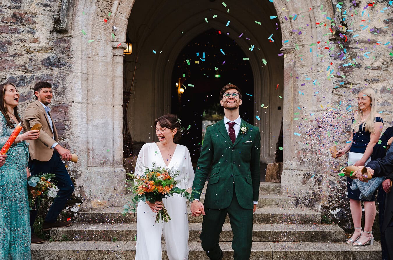 Wedding confetti pours down over the happy couple as they walk down the steps by Cheshire Wedding Photographer, Jake Timms Photography