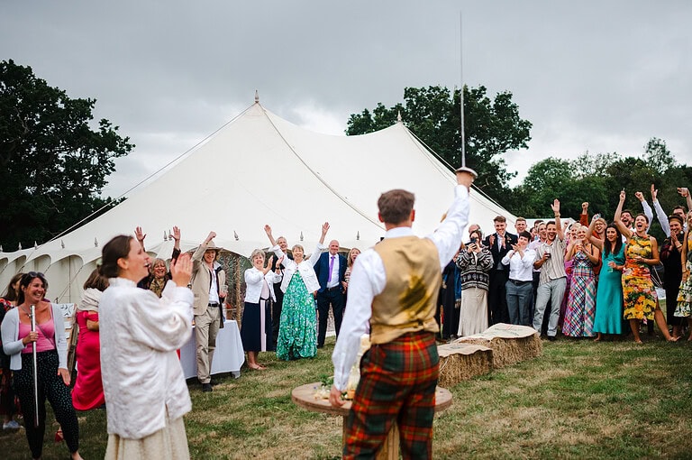 Groom raising the sword to his loved ones as they all cheer
