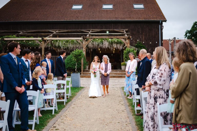 The mother of the bride walks her daughter down the aisle at Froginwell