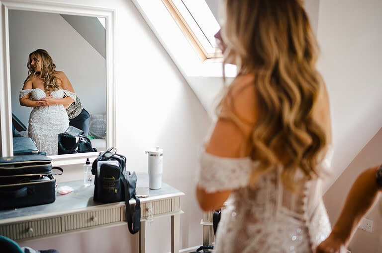 Bride is reflected in the mirrow as she gets wedding ready in the Cascade room in The Pear Tree in Purton - By Jake Timms Photography