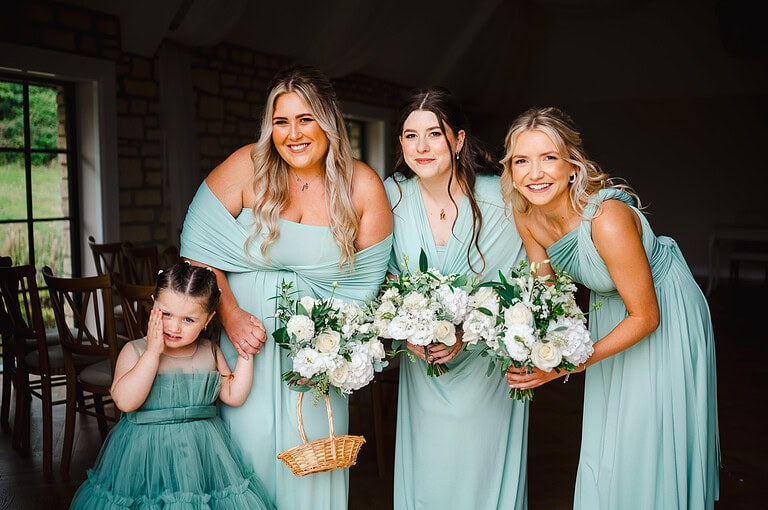 Bridesmaids look out towards the wedding ceremony before they walk the bride down the aisle