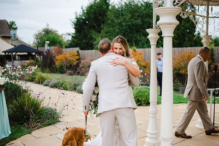 The bride hugs the groom as she reaches him at the end of the wedding aisle at the pear tree in Purton