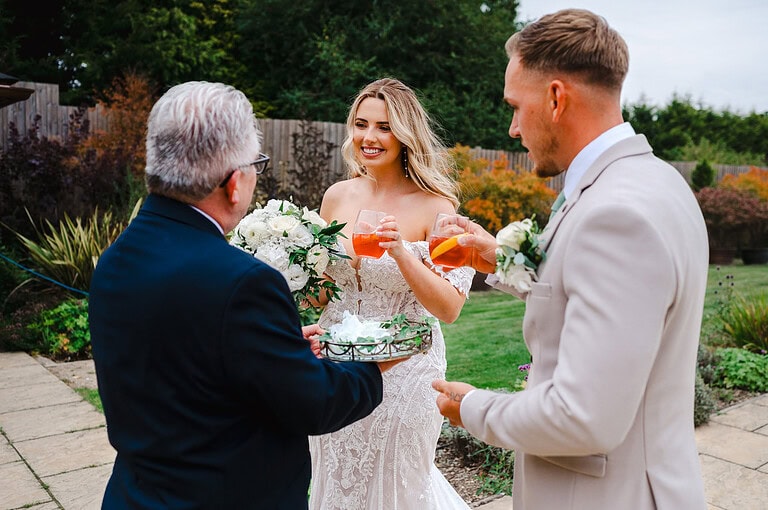 Bride and groom are greeted at the end of the aisle at The Pear Tree with celebration drinks