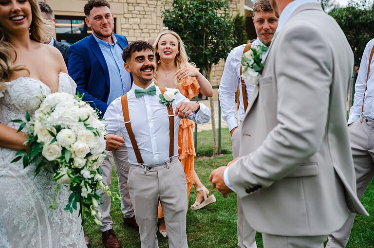 Wedding party laughing as he holds onto his braces