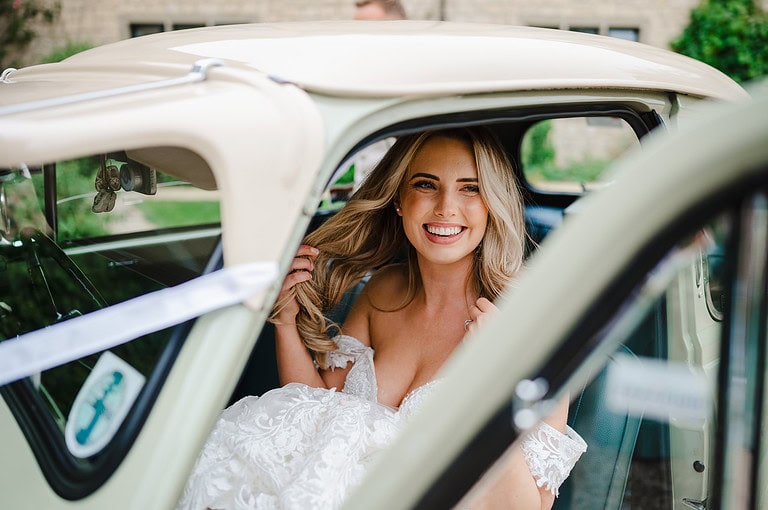 The bride happily gets into her vintage wedding car