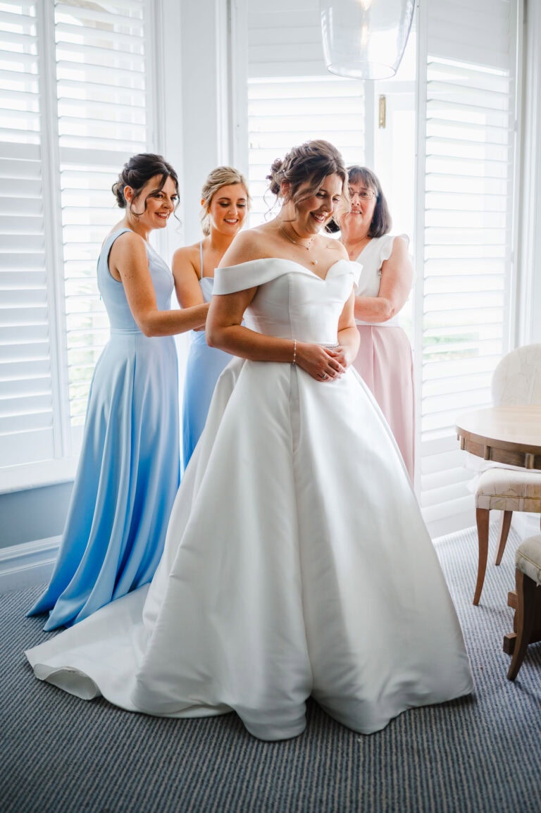 A beautiful moment as the bridesmaids help the bride get into her beautiful wedding dress at Harbour Hotel Padstow