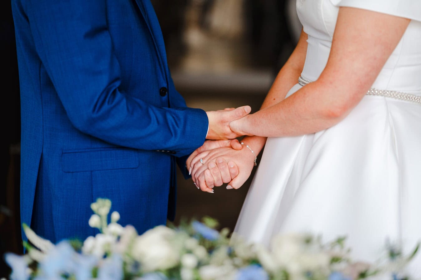 Up close of the bride and groom holding hands tightly during their wedding ceremony
