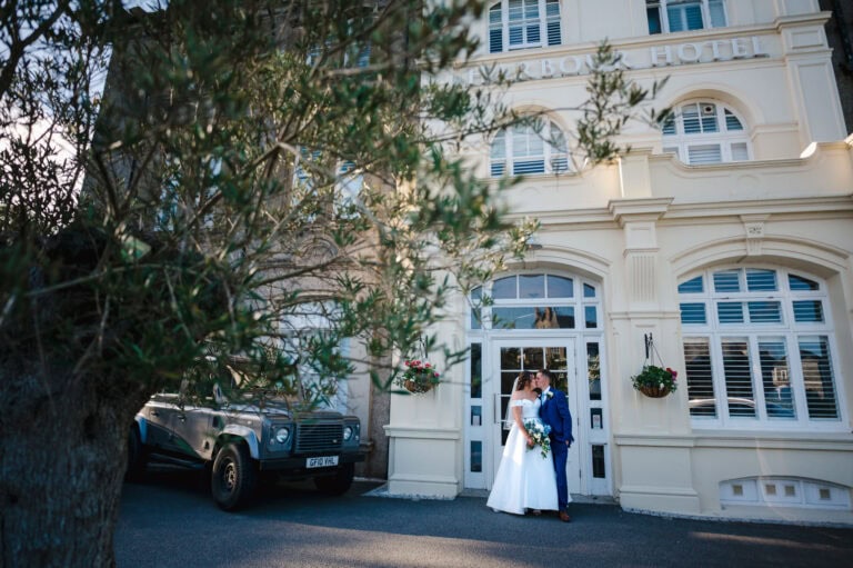 Standing in the doorway of the Harbour Hotel Padstow as the newlyweds go in for a kiss. By Cornwall Wedding Photographer, Jake Timms Photography