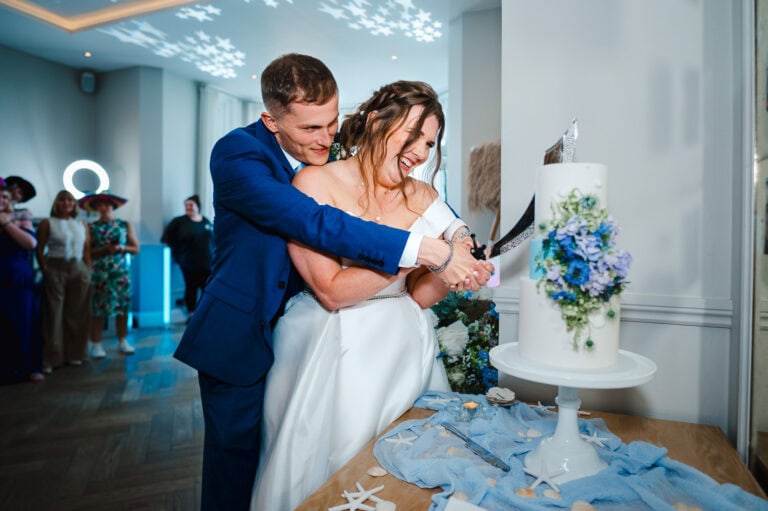 Bride and groom cut the wedding cake with a pirate sword by Cornwall Wedding Photographer, Jake Timms Photography