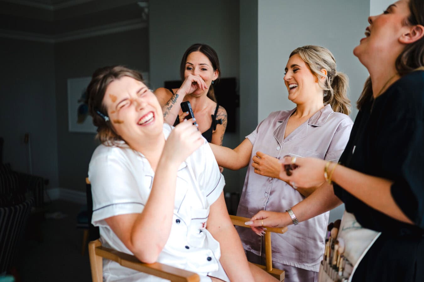 Everyone is laughing as they playback a video on one of the bridesmaids phones