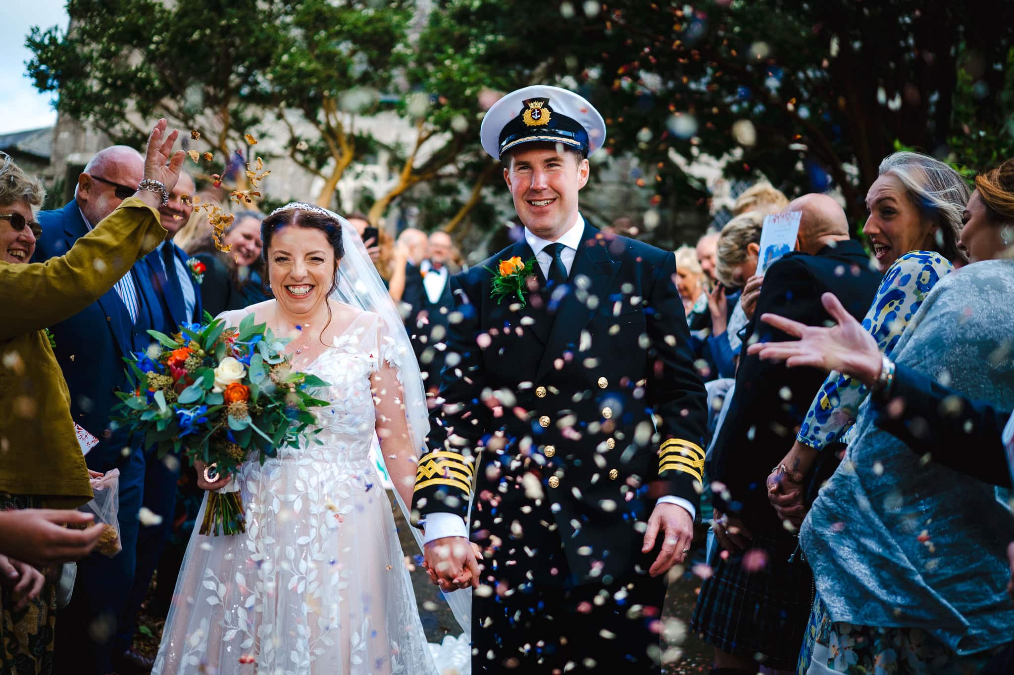 Confetti thrown high and wide as the couple walk down the confetti line celebrating their Mullion wedding